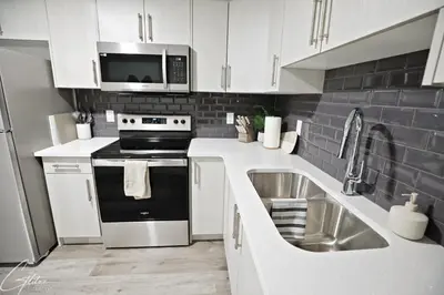 a white kitchen with a sink and a microwave at Beautiful Suite King Bed,Long Stays,Disney,Airport in Edmonton