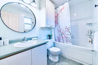 a bathroom with a sink and a toilet and a mirror at Three-Tree Villa-Central Location in Vancouver