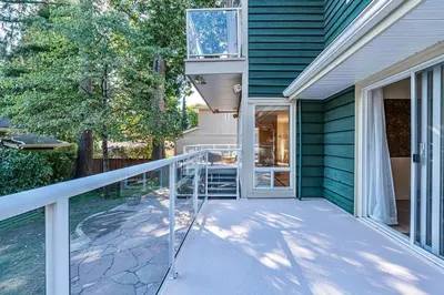 a balcony with a glass railing on a house at Three-Tree Villa-Central Location in Vancouver
