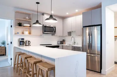 a kitchen with white cabinets and a bar with stools at Farwell's Spike by Revelstoke Vacations in Revelstoke