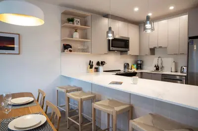 a kitchen with white cabinets and a table and chairs at Revy Mountain Retreat in Revelstoke