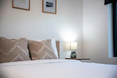 a white bed with pillows and a lamp on a table at Revy Mountain Retreat in Revelstoke