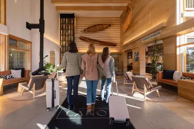 three women walking through a lobby with luggage at Hotel Canoe and Suites in Banff