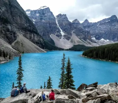 a group of people sitting on a rock near a lake at Immersed in the scenery of Canmore in Canmore