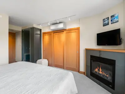 a bedroom with a bed with a fireplace and a tv at Ski In/Out, Steam Shower, Pool, Hot Tub, Sauna in Whistler