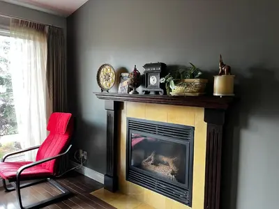 a living room with a fireplace and a red chair at citadel cozy quilt private bedroom in Calgary