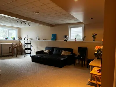 a living room with a black couch and a bar at citadel cozy quilt private bedroom in Calgary
