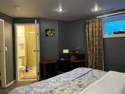 a bedroom with a bed and a desk and a bathroom at hidden valley new basement suite with private bathroom! in Calgary