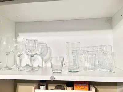 a bunch of glasses sitting on a shelf at Cozy Walkout suite with King bed, Kitchen, Parking & Patio in Calgary