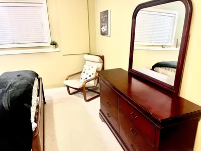 a bedroom with a dresser and a mirror at Cozy Walkout suite with King bed, Kitchen, Parking & Patio in Calgary