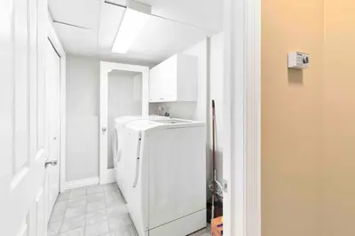 a white laundry room with a washer and dryer at Cozy Walkout suite with King bed, Kitchen, Parking & Patio in Calgary
