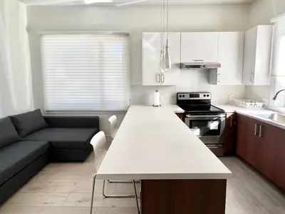 a kitchen with a white counter top and a couch at Brand New Modern Laneway House in Vancouver