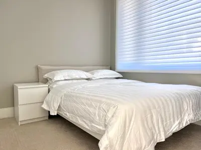 a bedroom with a white bed and a window at Brand New Modern Laneway House in Vancouver