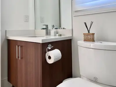 a bathroom with a toilet and a sink and a roll of toilet paper at Brand New Modern Laneway House in Vancouver