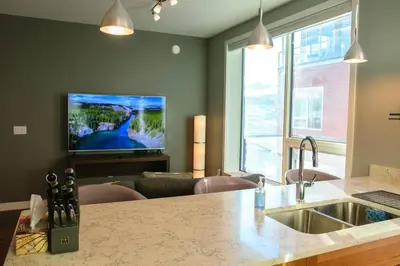 a kitchen with a sink and a living room at Bright Modern Stylish Condo in heart of Downtown (Center) in Whitehorse