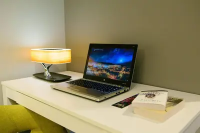 a laptop on a desk with a lamp and a book at Bright Modern Stylish Condo in heart of Downtown (Center) in Whitehorse