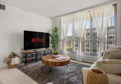 a living room with a tv and a couch and a table at Downtown Near Rogers Place with Covered Parking, Sleeps 6, Pool Table, Sauna, Gym, Two Bedrooms & More in Edmonton