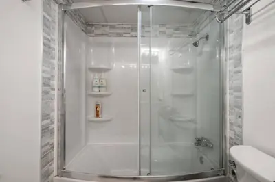 a shower with a glass door in a bathroom at Downtown Near Rogers Place with Covered Parking, Sleeps 6, Pool Table, Sauna, Gym, Two Bedrooms & More in Edmonton