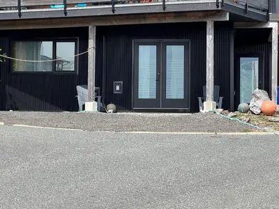 a building with a black door and windows on a street at Slack tide suite in Ucluelet