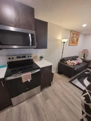 a kitchen with a stove and a living room with a couch at Cozy brand new 2 bedroom suite in Calgary in Calgary
