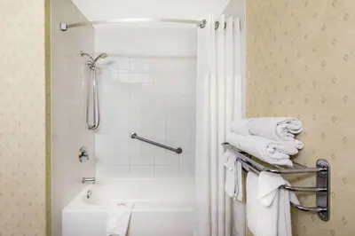 a bathroom with a shower and a toilet and towels at Ramada by Wyndham Clairmont/Grande Prairie in Clairmont