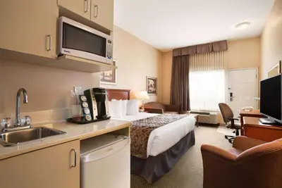 a hotel room with a bed and a sink at Ramada by Wyndham Clairmont/Grande Prairie in Clairmont
