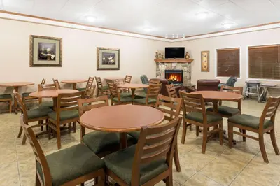 a restaurant with tables and chairs and a fireplace at Ramada by Wyndham Clairmont/Grande Prairie in Clairmont