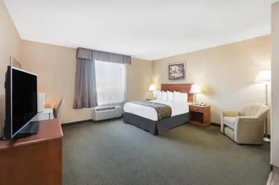 a hotel room with a bed and a flat screen tv at Ramada by Wyndham Clairmont/Grande Prairie in Clairmont