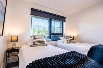 two beds in a room with a window at Alpine Haven by Revelstoke Vacations in Revelstoke