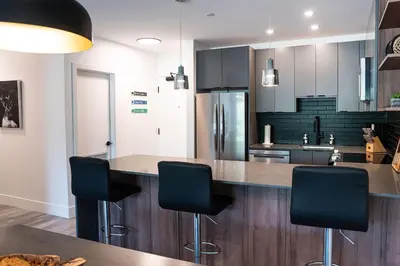 a kitchen with a counter with four chairs in it at Alpine Haven by Revelstoke Vacations in Revelstoke