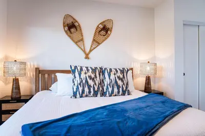 a bedroom with a bed with blue sheets and two lamps at Alpine Haven by Revelstoke Vacations in Revelstoke