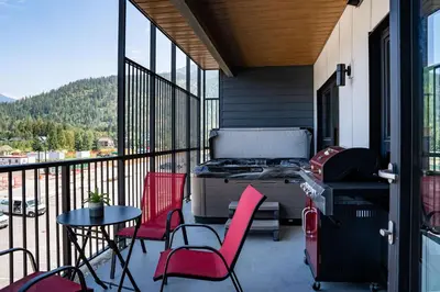 a patio with chairs and a grill on a balcony at Alpine Haven by Revelstoke Vacations in Revelstoke