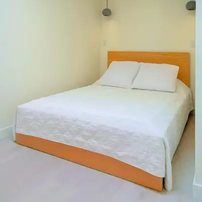 a bed with white sheets and a wooden headboard at Newly Renovated 2 Bedroom Condo in Japantown! Near Railtown & Gastown! in Vancouver