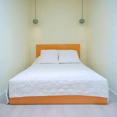 a bed in a white room with a wooden headboard at Newly Renovated 2 Bedroom Condo in Japantown! Near Railtown & Gastown! in Vancouver