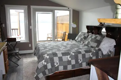 a bedroom with a bed and a table and windows at Orca Lodge in Sointula
