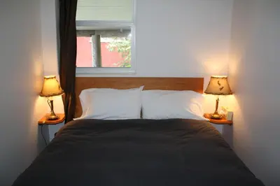 a bedroom with a bed with two lamps on both sides at Orca Lodge in Sointula