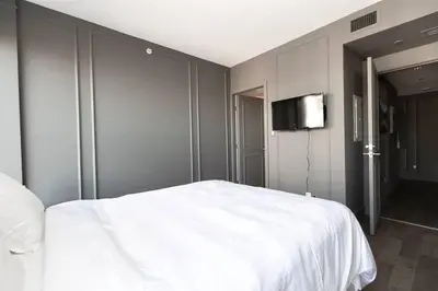 a bedroom with a white bed and a flat screen tv at Waterfalls Hotel in Downtown With Stunning Views! in Victoria