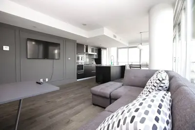 a living room with a couch and a table and a kitchen at Waterfalls Hotel in Downtown With Stunning Views! in Victoria