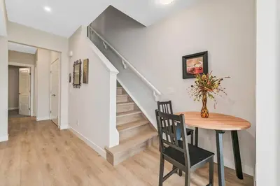 a dining room with a table and a staircase at Brand New Executive Suite in Calgary