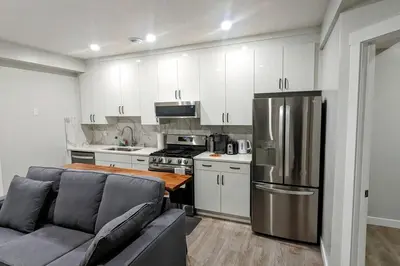 a kitchen with a couch and a stainless steel refrigerator at Cozy basement for a lovely stay & perfect for WFH in Edmonton