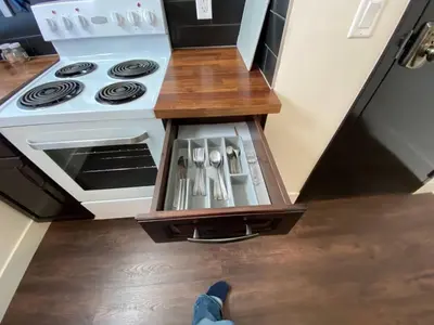 a person is standing in front of a stove in a kitchen at Brand New 1 Br 1 Bath Close To All Walkable in Edmonton