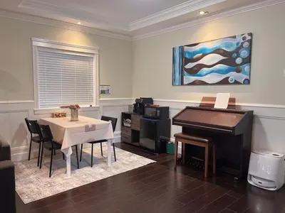 a dining room with a table and a piano at Near Skytrain and QUIET Private Bedroom Ensuite BathRM, Free Wifi & Coffee, Cozy in Burnaby