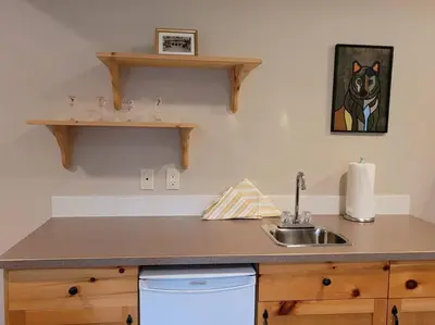 a kitchen with a sink and a dog painting on the wall at Pine Cone Cabin by StayIn in Radium Hot Springs