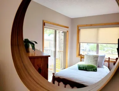 a mirror in a bedroom with a bed and a window at Pine Cone Cabin by StayIn in Radium Hot Springs