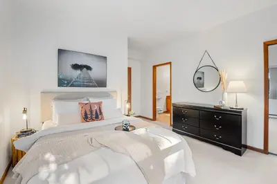 a white bedroom with a large bed and a dresser at Desirable Blueberry Hill in Whistler