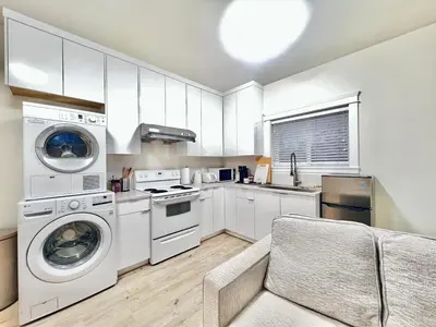 a kitchen with white appliances and a couch at Si & Daniel Home Near YVR Airport & Skytrain Separate Entry Free Parking in Richmond