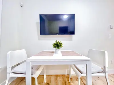 a white dining room table with two chairs and a tv at Si & Daniel Home Near YVR Airport & Skytrain Separate Entry Free Parking in Richmond