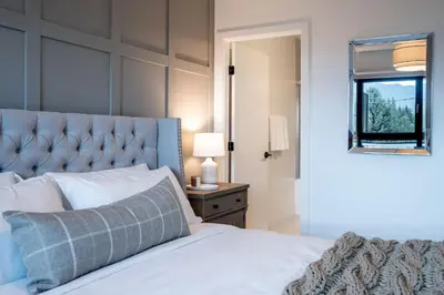 a bedroom with a bed with a blue headboard and a window at Stoked 4Ever - Revelstoke Condo (+Hot Tub) in Revelstoke