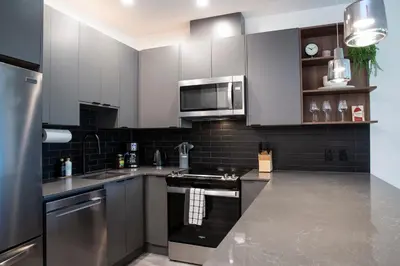 a kitchen with white cabinets and stainless steel appliances at Selkirk Powder Dream - Cozy Condo (+Hot Tub) in Revelstoke