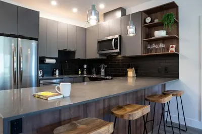a kitchen with a counter with stools in it at Selkirk Powder Dream - Cozy Condo (+Hot Tub) in Revelstoke